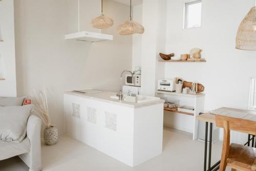 a white kitchen with a sink and a table at BeachHouse Geragera in Kobe