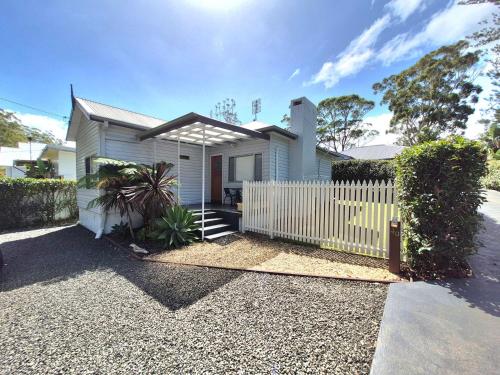 a white house with a fence in front of it at Shamrose Cottage - Huskisson in Huskisson