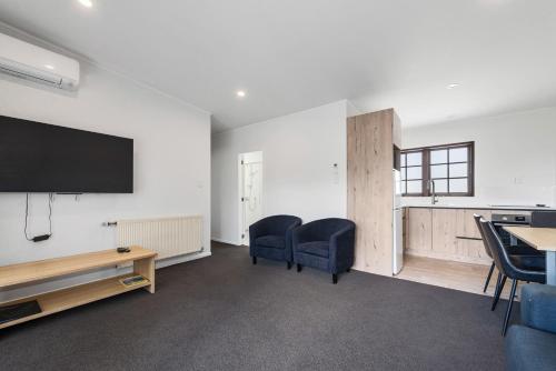 a living room with chairs and a flat screen tv at Wylie Court Motor Lodge in Rotorua