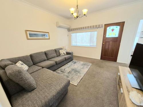 a living room with a couch and a television at Shamrose Cottage - Huskisson in Huskisson