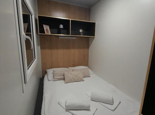 a small room with a bed with white sheets and pillows at Gabrijela House in Pirovac
