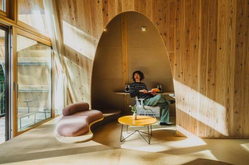 a person sitting at a table in a room with a mirror at SANU 2nd Home 軽井沢1st in Oiwake