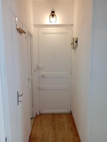 un couloir vide avec une porte blanche et une lumière dans l'établissement Appartement 2 pièces rénové, à Nantes