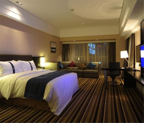 Holiday Inn Express Shenyang Golden Corridor, an IHG Hotel في شنيانغ: غرفه فندقيه بسرير واريكه