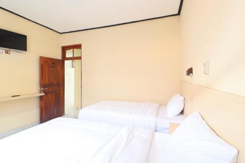 two beds in a room with a tv at Townhouse Oak Legian Near Legian Beach Formerly Sayang Maha Merta in Legian