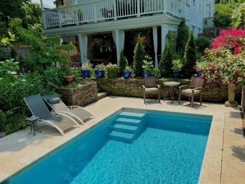 a swimming pool with chairs and a table in a yard at Palazzo Hudson - Luxury Pool, Hot Tub, and Sauna in Hudson