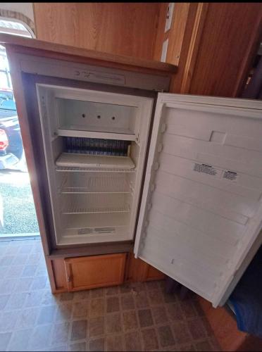 an empty refrigerator with its door open in a kitchen at Casa Rodante Roca Azul in Jocotepec