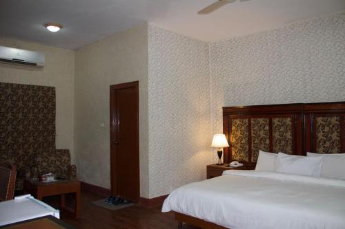 a hotel room with a bed and a table with a lamp at Margalla View Motel in Islamabad