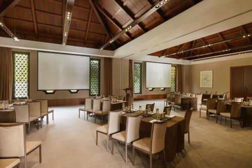 a restaurant with tables and chairs and a projection screen at Raffles Hainan Clear Water Bay in Sanya