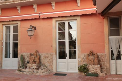 a pink building with two statues outside of it at Hostal Plaja i Pati de Can Plaja in Palafrugell
