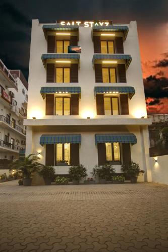 a white building with blue balconies in front of it at Saltstayz Select - Nehru Place & New Friends Colony in New Delhi