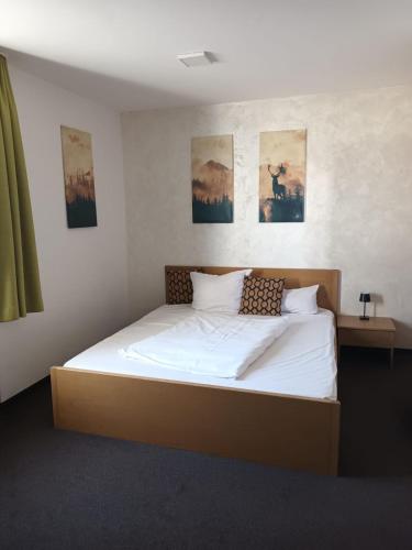 a bed in a bedroom with paintings on the wall at Zur Post Kümmersbruck Hotel & Tiny Houses in Kümmersbruck