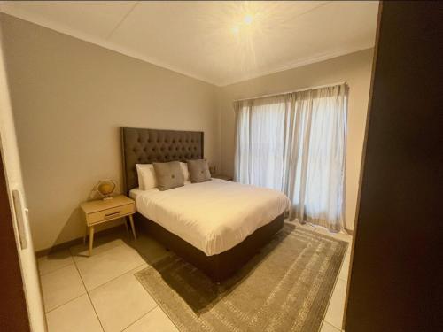 a bedroom with a large bed and a window at 16 Elizabeth Place - Beautiful and spacious self catering 3 bedroom unit next to Kyalami Racetrack with free WiFi - swimming pool gym and restaurant - Perfect for a big family in Midrand Waterfall in Midrand