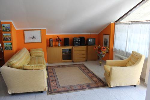 Moie的住宿－Anna Rita B&B，客厅配有两把椅子和橙色墙壁