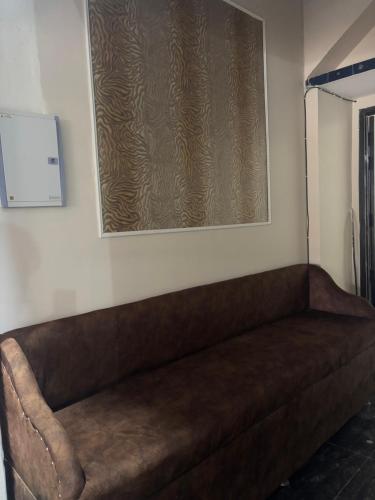 a brown couch in a room with a picture on the wall at Radha Madhavam Luxurious Boutique Stay in Mathura