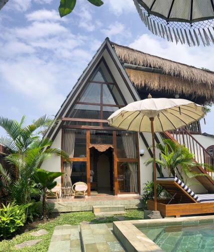 a house with a pool and an umbrella at The Phalosaa Villa in Ngaglik