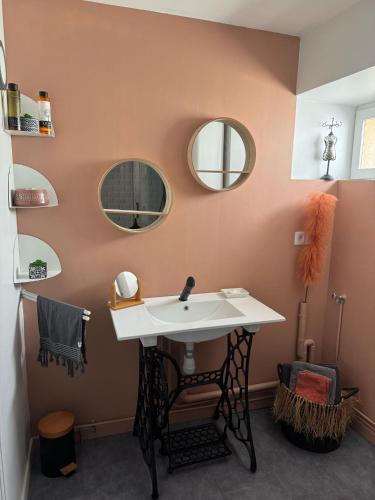 une salle de bain avec un lavabo et des miroirs au mur dans l'établissement La Casa del Rio, à Durtal