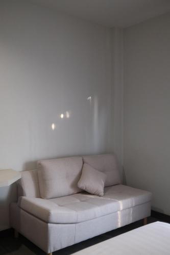 a white couch in a room with a white wall at Socool Grand Hotel in Nang Rong