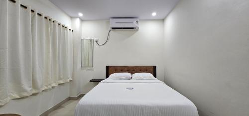 a white room with a bed in a room with a tv at Vizag's DESTINY INN in Visakhapatnam