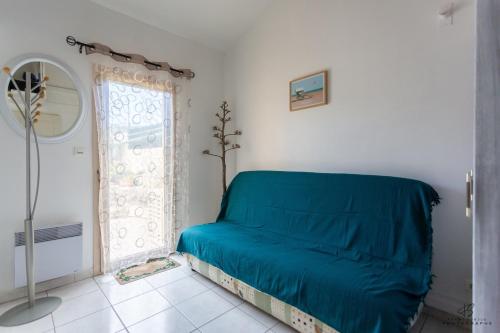 a blue bed in a white room with a window at Le Reflet du Canigou - Leucate - Vue , Terrasses , Parking in Leucate