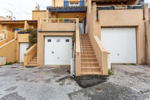 a house with two garage doors and a staircase at Le Reflet du Canigou - Leucate - Vue , Terrasses , Parking in Leucate