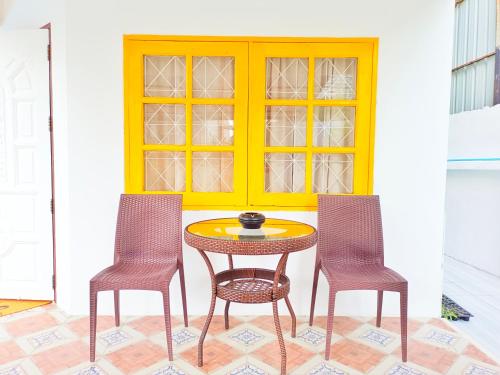 a table and two chairs in front of a yellow door at Retreat House 81 - BTS Onnut in Bangkok