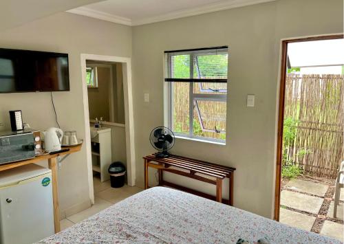 a bedroom with a bed and a desk and a window at Wamelia Guesthouse in Bloemfontein