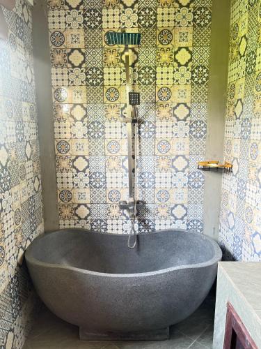 a bath tub in a bathroom with a tiled wall at The Phalosaa Villa in Ngaglik