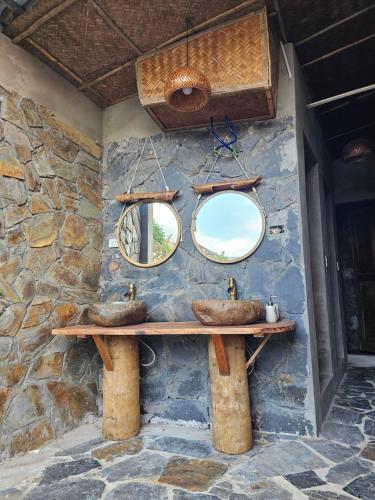 a bathroom with two sinks on a stone wall at Pu Luong Serenity Lodge in Pu Luong