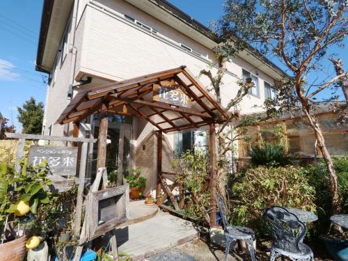 a wooden arbor in front of a building at ペンション花多來 in Shima