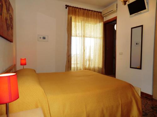 a bedroom with a yellow bed and a window at B&B Oasi in Marina di Palma