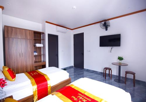 a hotel room with two beds and a flat screen tv at Khách sạn Tiến Đạt in Mèo Vạc