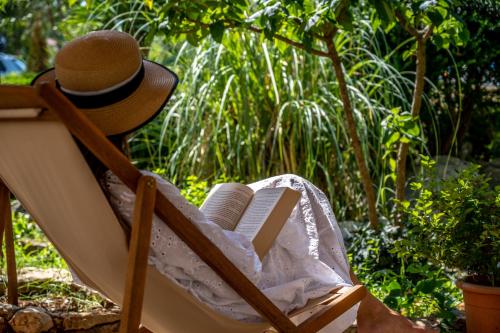 a person sitting in a chair with a hat and a book at Kalpic Suites & Villa in Lozovac