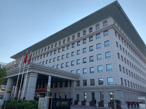 a large white building with a flag in front of it at Cozy Hotel Xiamen in Xiamen