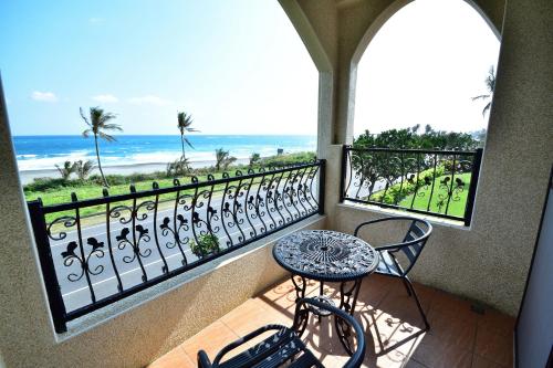 a balcony with a table and chairs and the ocean at Ji Li Ya Lan Homestay in Chenggong