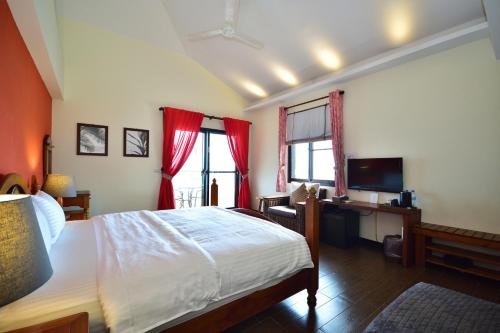 a bedroom with a bed and a desk with a television at Ji Li Ya Lan Homestay in Chenggong