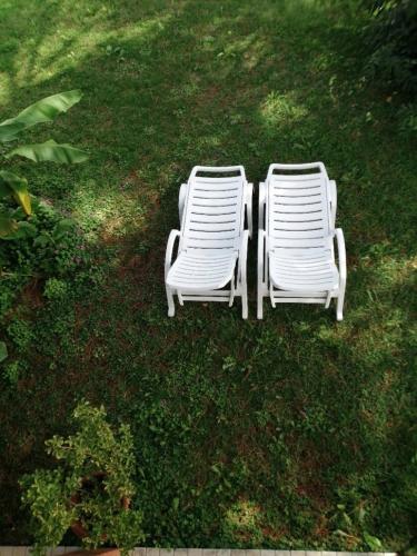 two white lawn chairs sitting in the grass at Comfortable house - garden and parking in Farra di Soligo