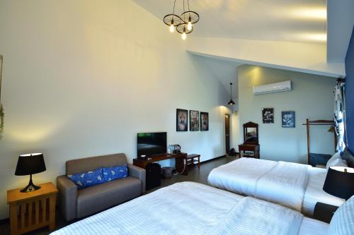 a bedroom with two beds and a couch and a tv at Ji Li Ya Lan Homestay in Chenggong