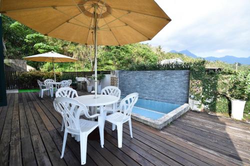a table and chairs with an umbrella on a wooden deck at Ji Li Ya Lan Homestay in Chenggong