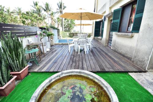 a wooden deck with a table and an umbrella at Ji Li Ya Lan Homestay in Chenggong