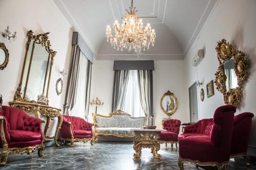 a living room with red chairs and a chandelier at Palazzo Angelelli in Gallipoli