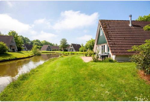 a house on the side of a river next to a house at Vakantiewoning Meerrust in Gramsbergen