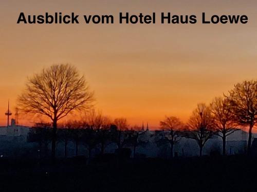 a sunset with trees in the foreground and aioch at Hotel Haus Loewe in Frechen