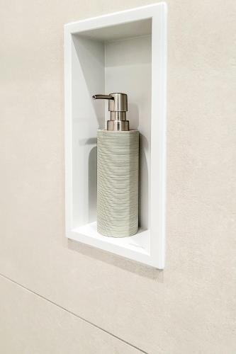 a soap dispenser in a white holder on a wall at Säntisblick Apartment in Schwarzach