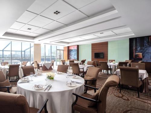 a dining room with tables and chairs and a television at Cordis, Foshan, Lingnan Tiandi - Free Shuttle Bus to Canton Fair in Foshan
