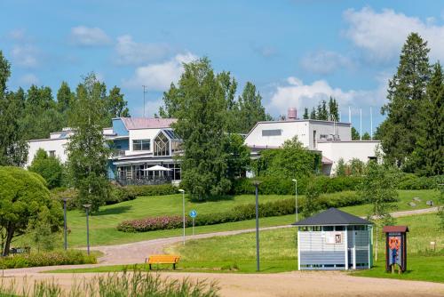 a large white house with a building in the background at Hotel Kurikka in Kurikka