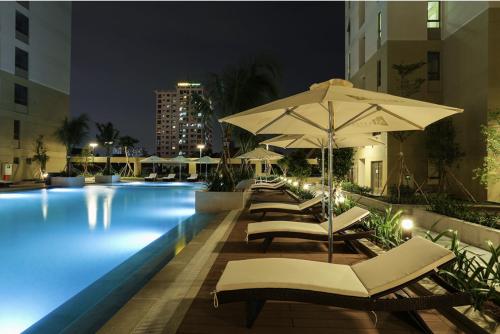 ein Swimmingpool mit Liegestühlen und Sonnenschirm in der Unterkunft SPACIOUS Home in Ho-Chi-Minh-Stadt