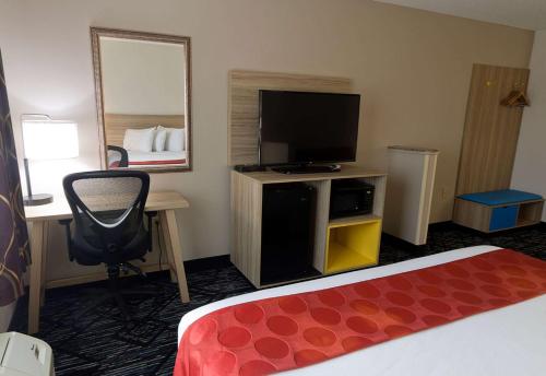 a hotel room with a bed and a desk and a television at Ramada Limited Decatur in Forsyth