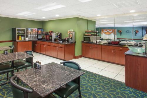 a restaurant with tables and chairs and a kitchen at Ramada Limited Decatur in Forsyth