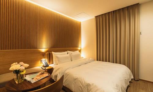 a hotel room with a bed and a table with a phone at Hound Hotel chuncheon in Chuncheon